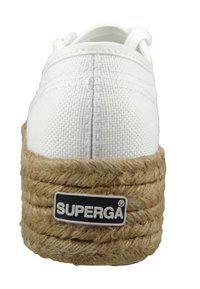 Baskets en toile blanche avec une épaisse semelle en jute tressé. Logo "SUPERGA" bien en vue sur le côté. Bout rond et design minimaliste.