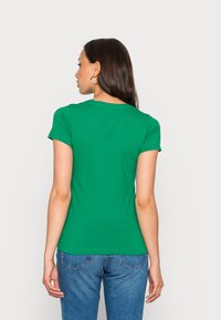 T-shirt verde de mangas curtas com gola redonda, design ajustado e textura suave. A vista traseira apresenta um tecido liso e um corte clássico simples.