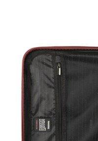 Valigia da viaggio rossa con interno nero. Dotata di chiusure a zip, tessuto liscio e un'etichetta sul lato interno.