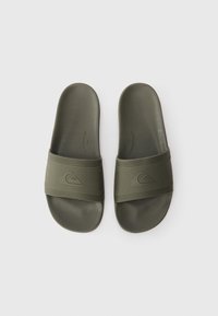O pereche de sandale slide de culoare verde măsliniu cu barete texturate împodobite cu un logo în formă de val, plasate una lângă alta pe un fundal alb.