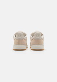 Footwear with a soft peach suede upper and cream accents. Features a textured design and a rubber sole with a light brown bottom.
