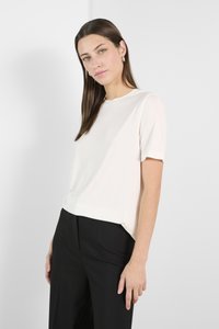 Kortærmet, cremefarvet bluse lavet af glat stof, med en rund halsudskæring. Kombineret med skræddersyede sorte bukser, minimalistisk design.