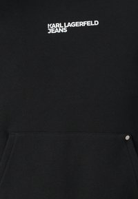 Schwarzer Sweatshirt mit Kängurutasche, weißem "KARL LAGERFELD JEANS"-Text und einem silbernen Akzent in der Nähe der Tasche. Weicher, strukturierten Stoff.