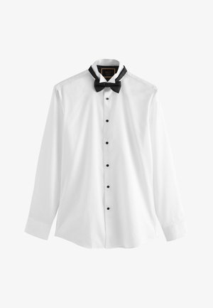 Hvid skjorte med lange ærmer med sorte knapper og en sort færdigbundet butterfly omkring kraven, vist på en hvid baggrund.