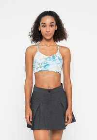 Világoskék és zöld virágmintás crop top vékony pántokkal, szürke, harangszoknyával párosítva, amely gomb- és redőmintázattal rendelkezik.