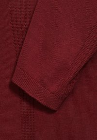 Jersey de punto burdeos con puños acanalados y patrones texturizados a lo largo del cuerpo, que destaca por un acabado de tejido suave y liso.