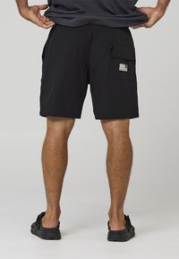Schwarze Badeshorts mit großer Seitentasche, Klappe und Druckknopfverschluss, elastischem Bund und glattem, leichtem Stoff.