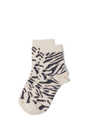 Beige Knöchelsocken mit auffälligem schwarzem Zebramuster, flach auf weißem Hintergrund ausgebreitet.
