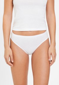 Bijela pamučna bikini gaćice s glatkom, laganom teksturom i kontrastnim bijelim elastičnim pojasom. Minimalistički i osnovni dizajn.