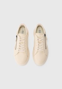 Pair of beige leather sneakers with laces and side zippers, viewed from above on a plain white background.