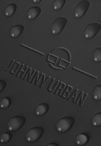 Svart gummimatta med strukturerade droppmönster och präglad "JOHNNY URBAN"-logotyp. Slät, hållbar yta som är idealisk för olika användningsområden.