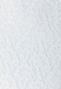 Tissu en dentelle blanche avec un motif floral comprenant des roses et des feuilles, montrant une texture détaillée et un design tissé complexe.