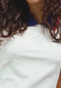 Biele polo tričko s modrým golierom; na ľavej hrudi sa nachádza logo Adidas. Hladká textúra látky s minimálnymi dizajnovými prvkami.