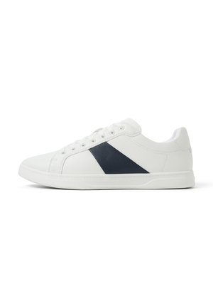 Zapatillas de cuero blancas con un panel diagonal azul marino, puntera redonda y cierre de seis ojales. Textura suave y diseño de perfil bajo.