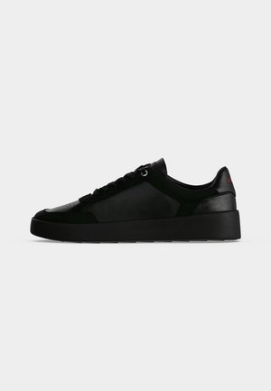 Sort lavtop sneaker med tyk sål, snørelukning foran og subtile teksturerede sidepaneler mod en lys baggrund.