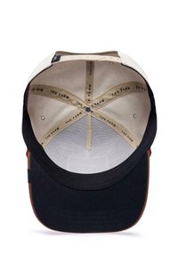Cappellino da baseball nero e crema con visiera curvata, dotato di un interno beige con testo del marchio ripetuto e un piccolo dettaglio a bottone nella parte superiore.