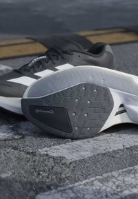 Chaussures de sport noir et blanc sur l'asphalte, montrant la semelle avec une adhérence texturée et un détail de marque "Continental".