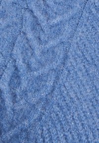 Tessuto in maglia blu con un motivo testurizzato, con fibre morbide che creano un aspetto accogliente e una leggera lucentezza nel materiale.