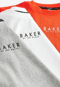 Trīs T-krekli sakrauti: viens oranžs, viens balts, viens pelēks; visi no kokvilnas ar ribotu apaļu kakla izgriezumu. Katrs no tiem ir ar melnu "BAKER by TED BAKER" logo.