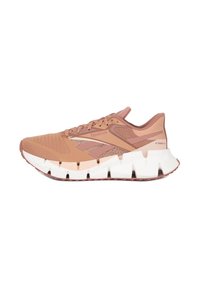 Bežecká obuv Reebok má svetlohnedý syntetický zvršok s sieťovanými akcentmi, hrubú bielu a hnedú podrážku a zaoblený dizajn päty pre podporu.