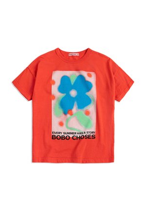 Rood T-shirt met korte mouwen, voorzien van een grote blauwe bloem en groene bladeren, oranje stippen en de tekst "ELKE ZOMER HEEFT EEN VERHAAL BOBO CHOSES."