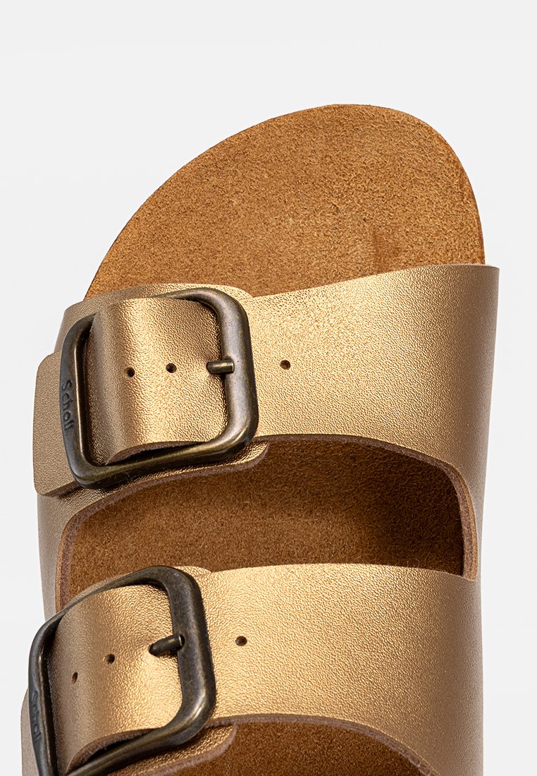 Sandales métalliques dorées avec deux sangles réglables, une surface texturée et une semelle en liège. Présente une accent de boucle en bronze foncé.