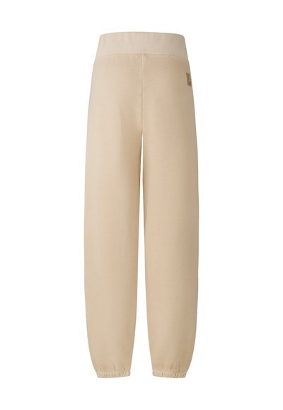 Beige sweatpants med bred elastisk talje, tætsiddende ankler og et lille logo-tag på hoften, lavet af blødt, tekstureret stof.
