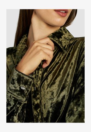 Dark green velvet shirt with a shiny texture, featuring a pointed collar and buttoned cuffs, accented by shiny silver button details.