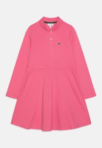 Robe polo longue à manches roses avec un col, un bustier ajusté, une jupe évasée et un petit logo de crocodile vert sur la poitrine gauche. Tissu hypoallergénique.