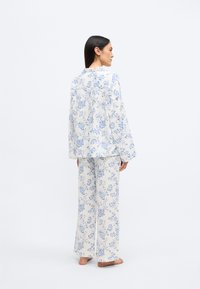 Ensemble de pyjama à motif floral comprenant un haut à manches longues ample et un pantalon à jambes larges en coton dans des tons de bleu et blanc.