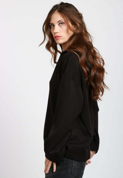 Felpe nere oversize in tessuto morbido con spalle scese e maniche lunghe, vestibilità ampia e polsini a costine.