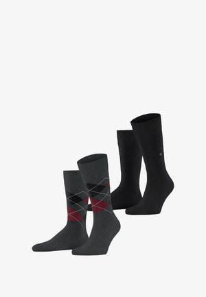 Dwie pary skarpet wyeksponowane: jedna para jest ciemnoszara w czerwono-czarny wzór argyle, druga to klasyczne czarne skarpetki.