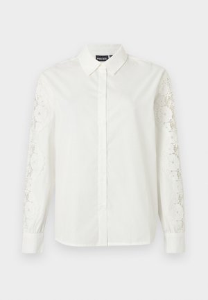 Camicia bianca con bottoni, collo con revers, maniche lunghe con dettagli in pizzo intricati e tessuto di cotone liscio.