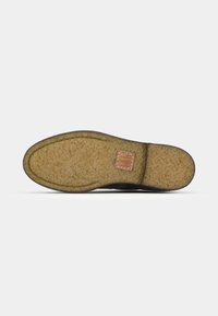 Suola di scarpa marrone scuro con una superficie texturizzata e un accento in pelle color tan. La suola è leggermente curva e presenta una finitura in gomma per una migliore aderenza.
