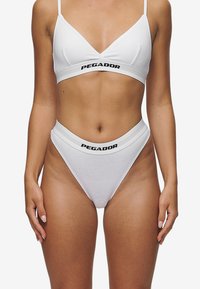 Bralet alb și chiloți de bikini cu talie înaltă, cu logo-ul negru "PEGADOR". Materialul este neted, cu un design minimalist și bretele subțiri.