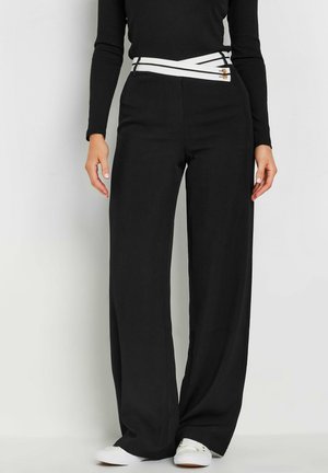 Zwarte wijde pantalons met een contrasterende witte gekruiste riem. Gemaakt van een gladde stof, met een hoge taille en strakke lijnen.