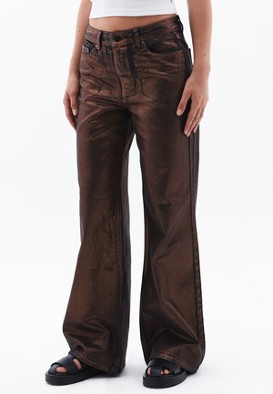 Bronzen metalen wijde jeans met een hoge taille, voorzakken en zichtbare stikseldetails. Gecombineerd met zwarte platform sandalen.