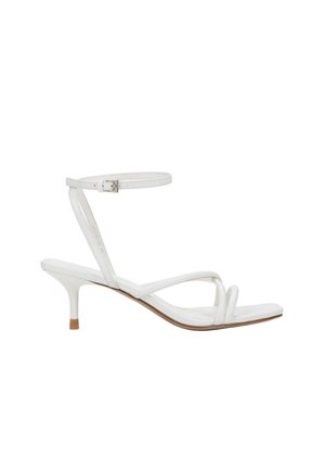 White open-toe sandal with low kitten heel, thin ankle strap with buckle, and two thin padded straps over the foot.