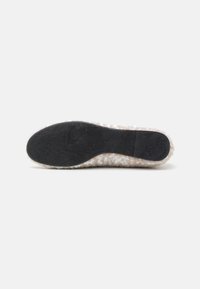 Talpa de sneaker cu un fund negru din cauciuc texturat, prezentând un model ondulat, înconjurată de un material superior texturat de o culoare deschisă.