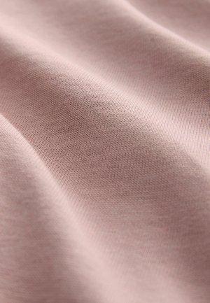 Lichtroze textiel stof met een gladde, iets gestructureerde oppervlakte, met fijne horizontale breipatronen en subtiele plooien.