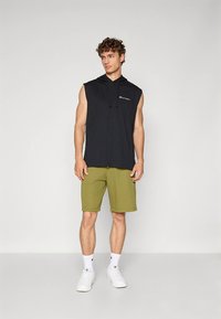 Sort ærmeløs hættetrøje med logo; olivengrønne shorts; hvide sportssokker og sneakers. Enkel design, afslappet pasform.