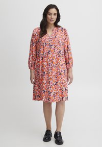 Rochie florală cu un model vibrant în nuanțe de roz, portocaliu și marin, cu decolteu în V, mâneci trei sferturi și o siluetă în formă de A.
