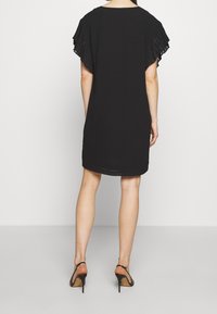 Svart klänning med avslappnad passform, veckade korta ärmar och rundad halsringning, med en mjuk textur och längd ovanför knäna.