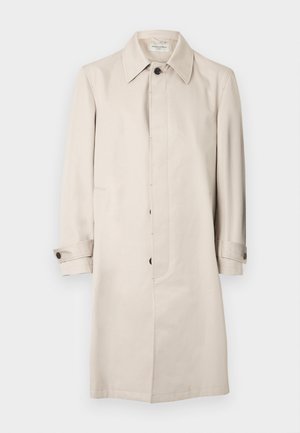Beige trenchcoat med knapper foran, lange ærmer og sidelommer. Har krave og op-rullede manchetter. Glat tekstur.