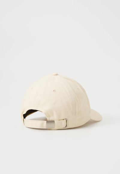 Beige cotton baseball cap with a curved visor, adjustable strap, and metal clasp at the back. Plain design with no patterns.