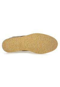 Suela de zapato de ante marrón claro con superficie texturizada y un material de goma amarillenta, presentando una forma redondeada y un diseño de tacos mínimo.