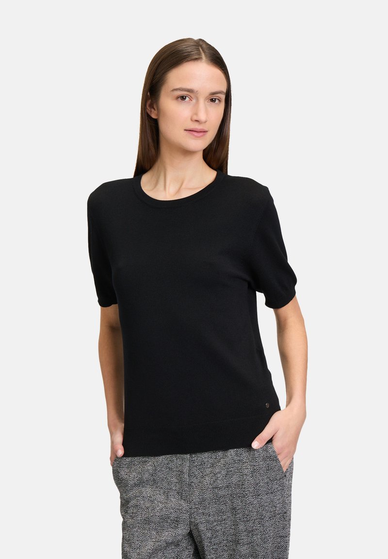 Top corto nero a maniche corte in maglia con scollo rotondo e vestibilità rilassata. Tessuto liscio con un sottile dettaglio del logo piccolo in fondo.