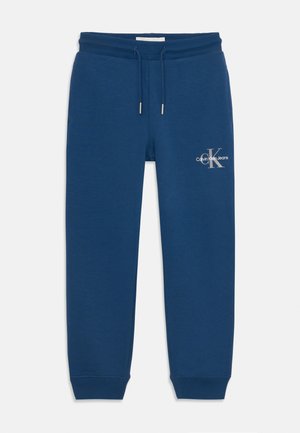 Námornícky modré tepláky vyrobené z jemnej zmesi bavlny, s elastickým pásom na sťahovanie, rebrovanými manžetami a logom na stehne.