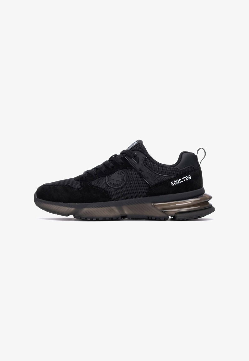 Zapatilla negra con parte superior de malla y ante, cordones texturizados, marca en relieve y una suela gruesa y translúcida para mayor amortiguación.