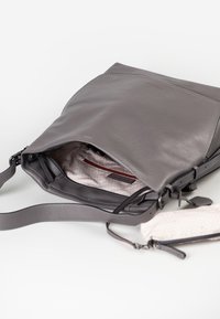 Graue Leder-Schultertasche mit flachem Design. Verfügt über eine Innentasche mit rotem Reißverschluss und gefüttertem Innenfutter. Verstellbarer Tragegurt ist enthalten.